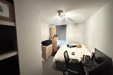 A cozy bedroom featuring a bed, a desk, and som...