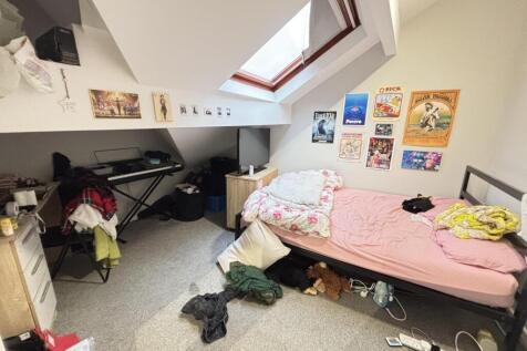 A cluttered bedroom with unmade bed and persona...