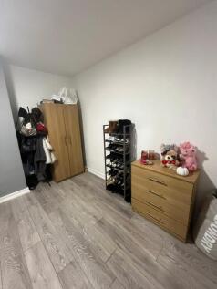 A cozy single bedroom with a wooden chest of dr...