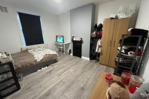 A modest bedroom with a single bed, desk, and w...