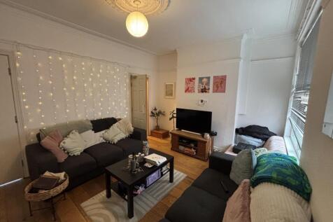 A cozy, well-lit living room featuring comforta...