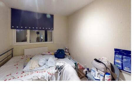 A modest single bedroom with a bed, a small des...