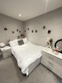 A spacious master bedroom featuring a comfortab...