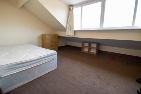 A cozy single bedroom with a large window allow...