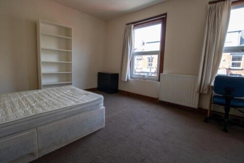 A well-lit bedroom with a large window, featuri...