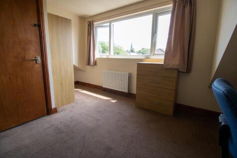 A modest bedroom with a large window providing ...