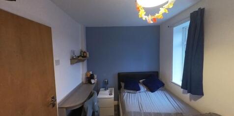 A cozy bedroom with a neatly made bed against a...