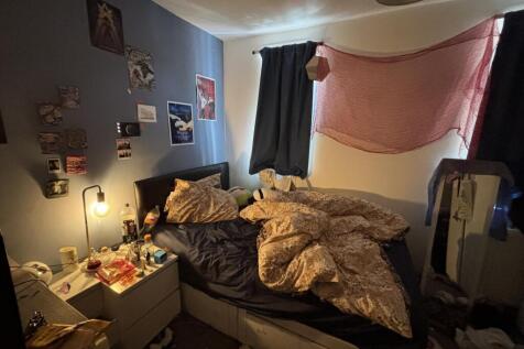 A cozy bedroom with a bed, nightstand, and some...