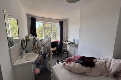 A cozy bedroom featuring a single bed, a small ...