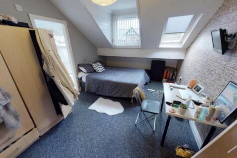 A cozy single bedroom with a neatly made bed, a...