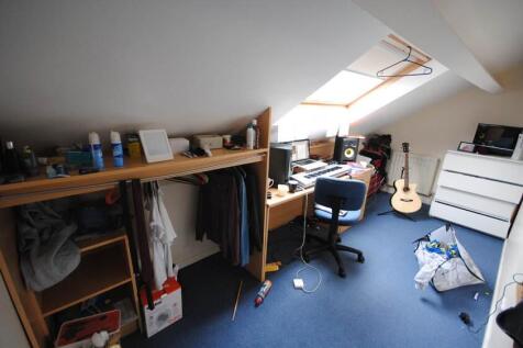 A cozy bedroom featuring a work desk and a guit...