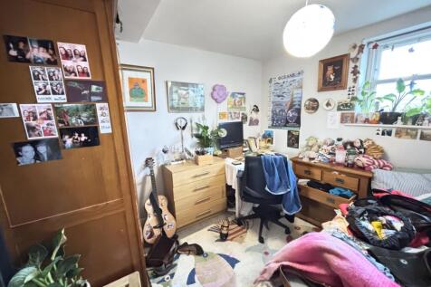 A cozy bedroom featuring a bed, study desk, and...