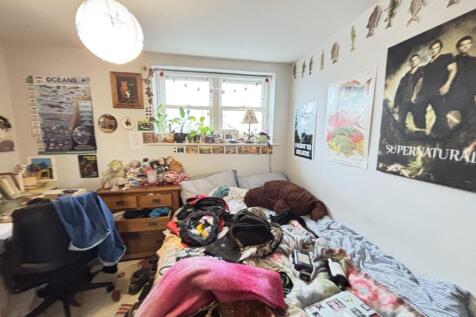 A cozy bedroom featuring a bed, desk, and perso...