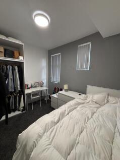 A bright and cozy bedroom featuring a neatly ma...