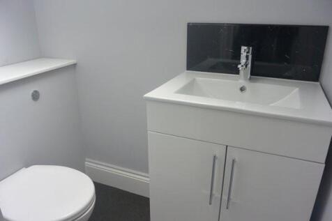 A modern, clean bathroom featuring a white sink...