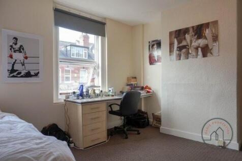 A cozy bedroom featuring a neatly made bed, a d...