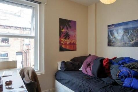 A cozy single bedroom featuring a bed with vari...