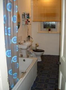 A modest bathroom featuring a bathtub with a co...