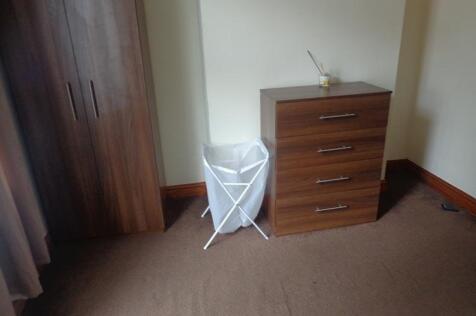 A cozy bedroom featuring a small chest of drawe...