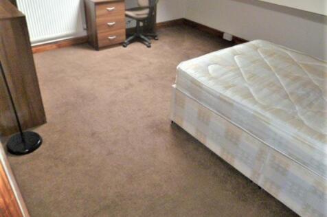 A modest bedroom featuring a single bed, a smal...