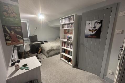 A cozy bedroom featuring a bed, a bookshelf, an...