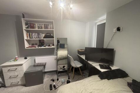 A well-lit bedroom featuring a large bed, a des...