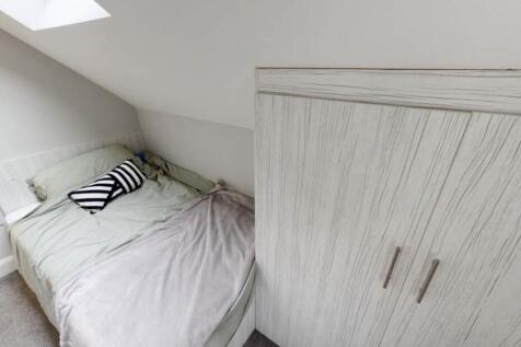 A cozy bedroom featuring a neatly made bed with...