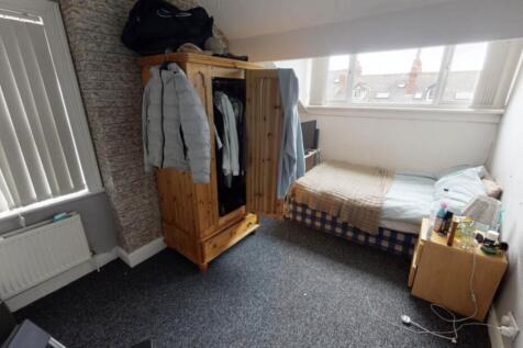 A well-lit bedroom featuring a single bed, a wo...