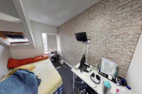 A compact bedroom featuring a bed with bedding,...