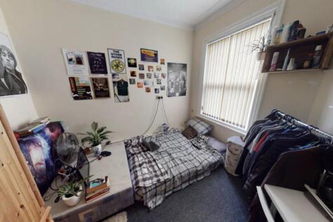 A cozy single bedroom featuring a bed with a ch...