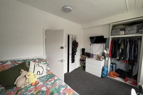 A tidy bedroom featuring a bed with colorful be...