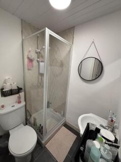 A compact bathroom featuring a shower enclosure...