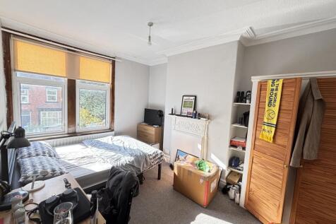 A cozy bedroom featuring a bed, a large window ...