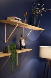 Stylish wall shelves mounted on a deep-blue pai...