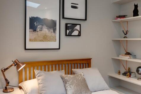 Bright, neatly styled bedroom with a wooden sla...