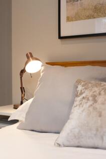 Stylish, neatly made bedroom with layered cushi...