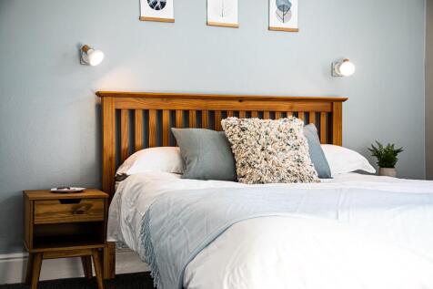 A cozy double bedroom featuring a wooden headbo...