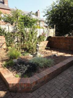 Sunny low-maintenance walled garden with raised...