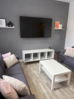 Bright, modern living room with grey feature wa...