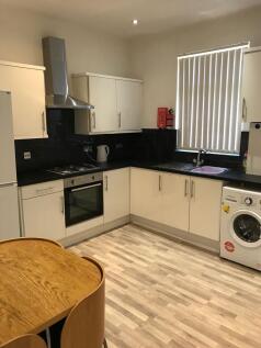 Modern fitted kitchen with white cabinets, blac...