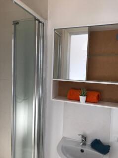 Bright, modern bathroom with a corner shower, m...