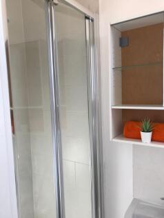 Bright, modern bathroom corner featuring a tile...