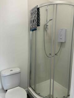 Bright, modern bathroom with a curved glass sho...