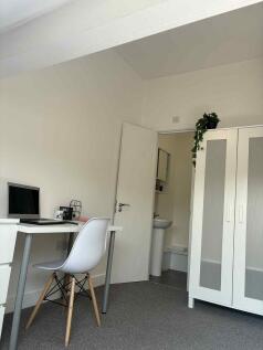 Bright, neutral bedroom with a tidy study area,...