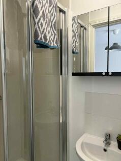 Bright, modern bathroom with a glass shower enc...