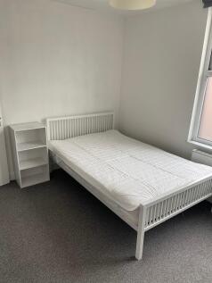 Bright, neat bedroom with a white double bed, s...