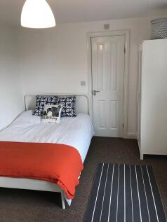 Bright, neatly styled bedroom with a white meta...