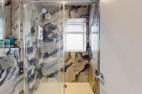 Modern walk-in shower with striking marble-effe...