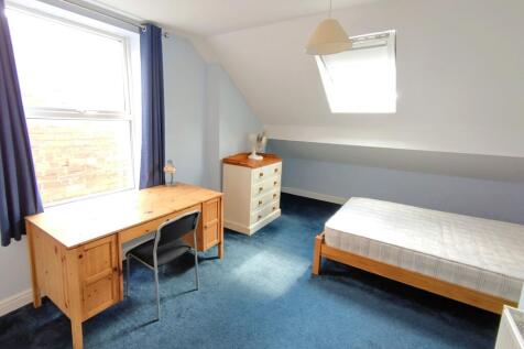 Bright attic bedroom with a large desk by a win...