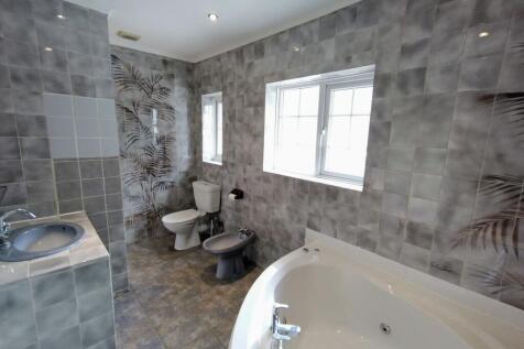 Bright, tiled bathroom featuring a large corner...